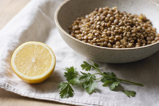 Citron coupé en deux devant un bol de lentilles et des brins de persil